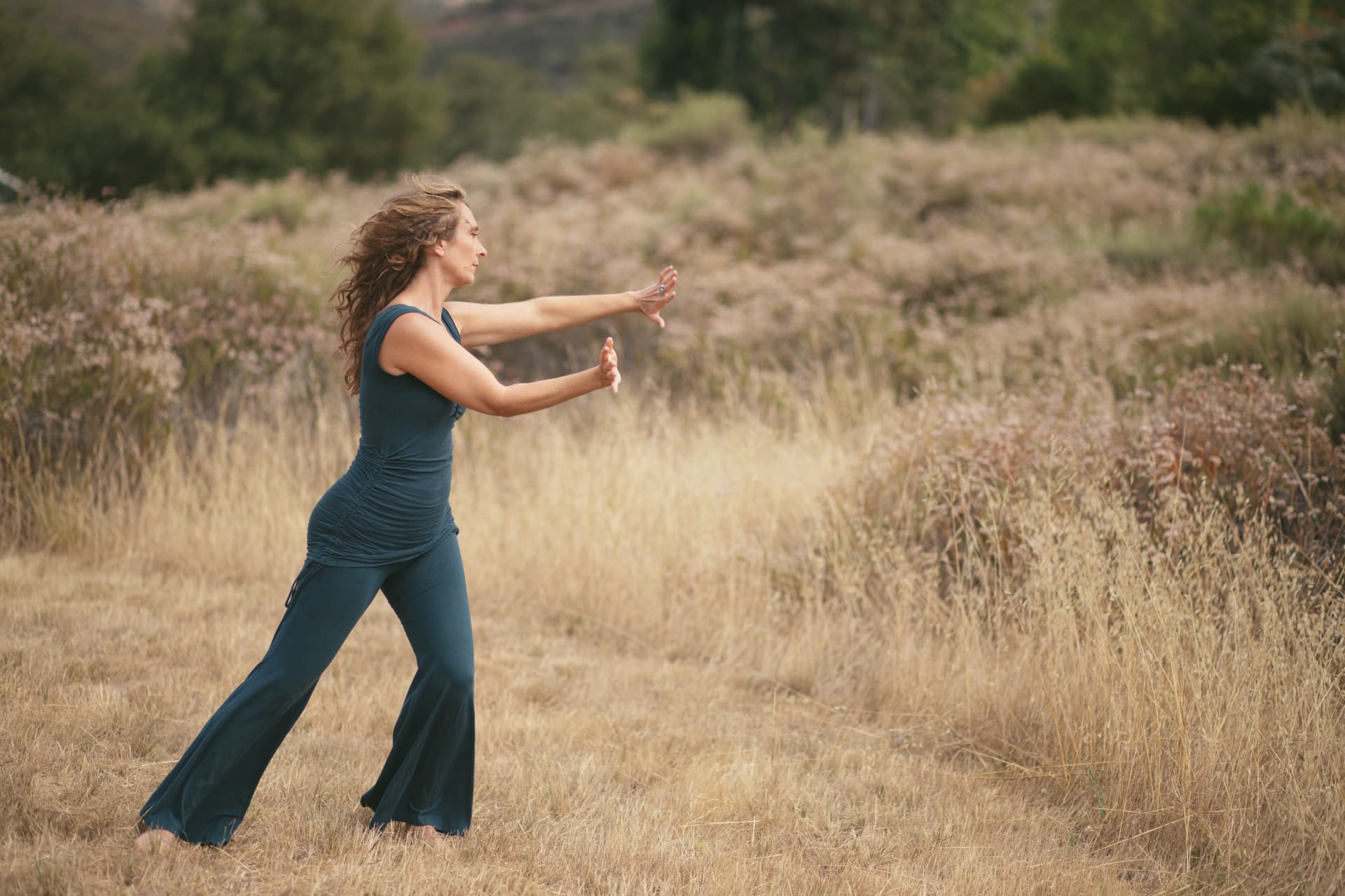 Jennica moving slowly in a dry grass field with arms extended